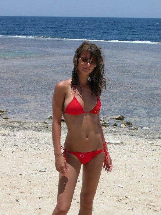 Секси девочка стоит в красном на пляже